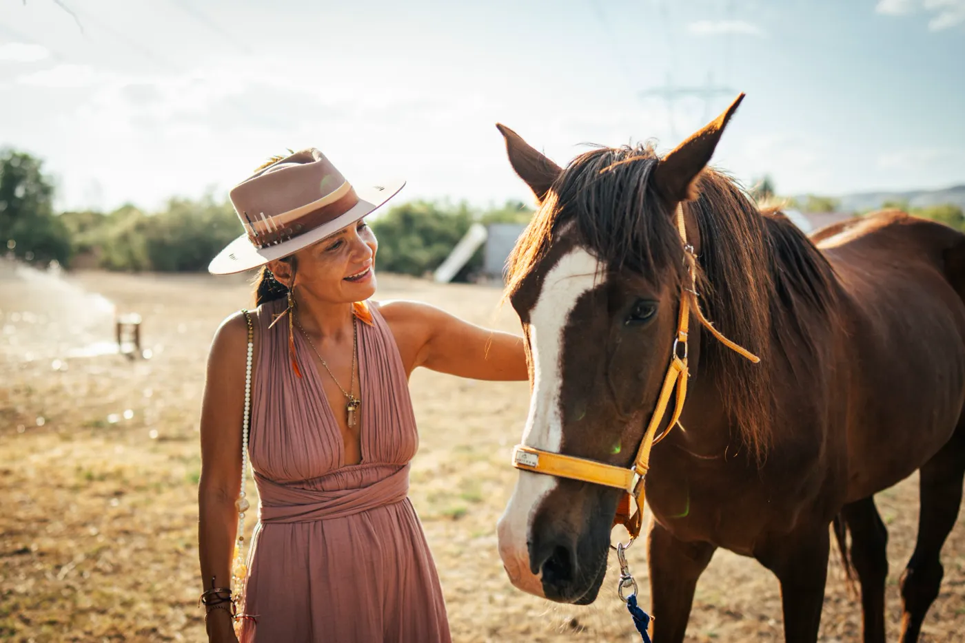 A woman smiling beside a chestnut horse