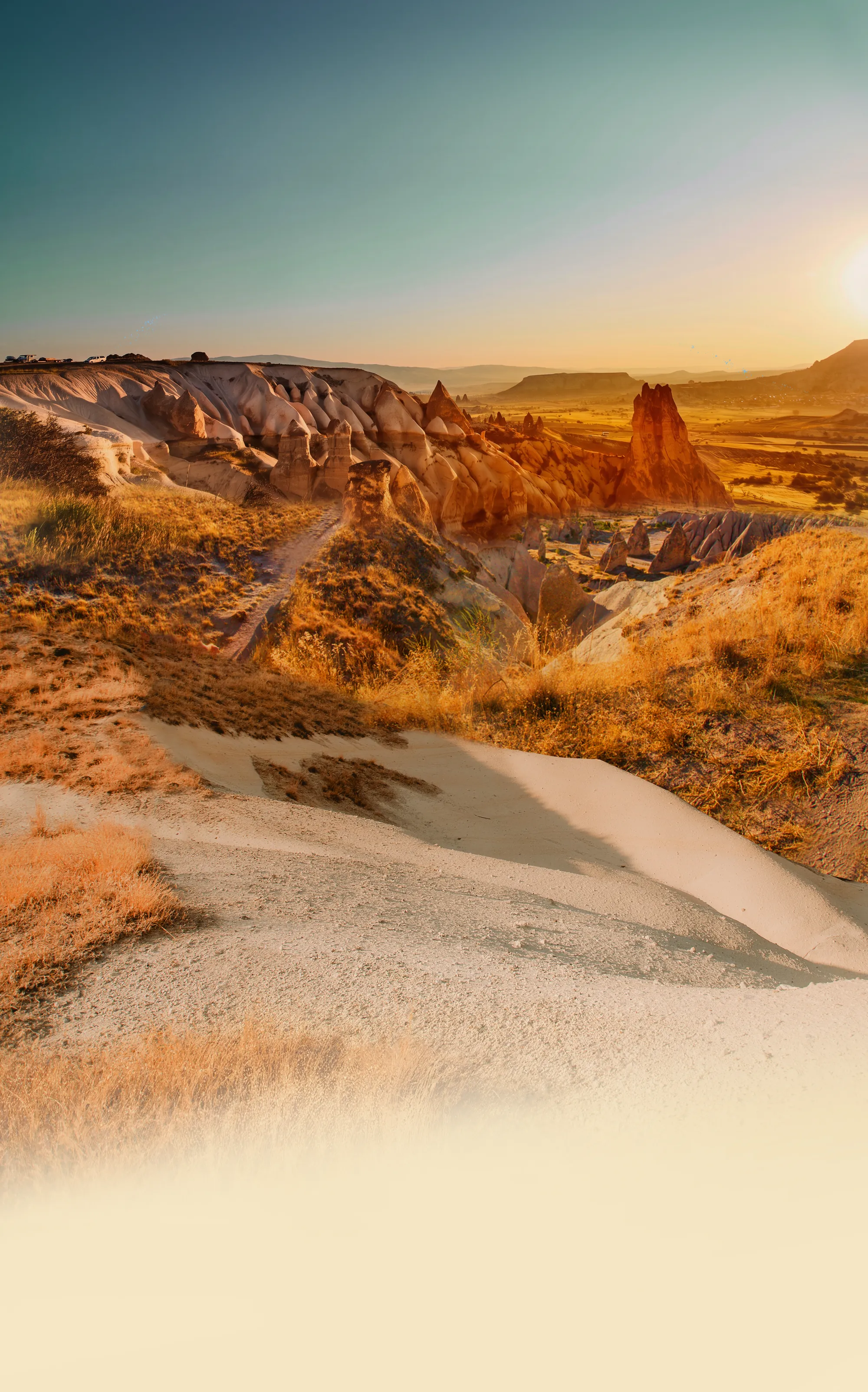 Sunrise over the same valley, hot air balloons lifting above the rocks